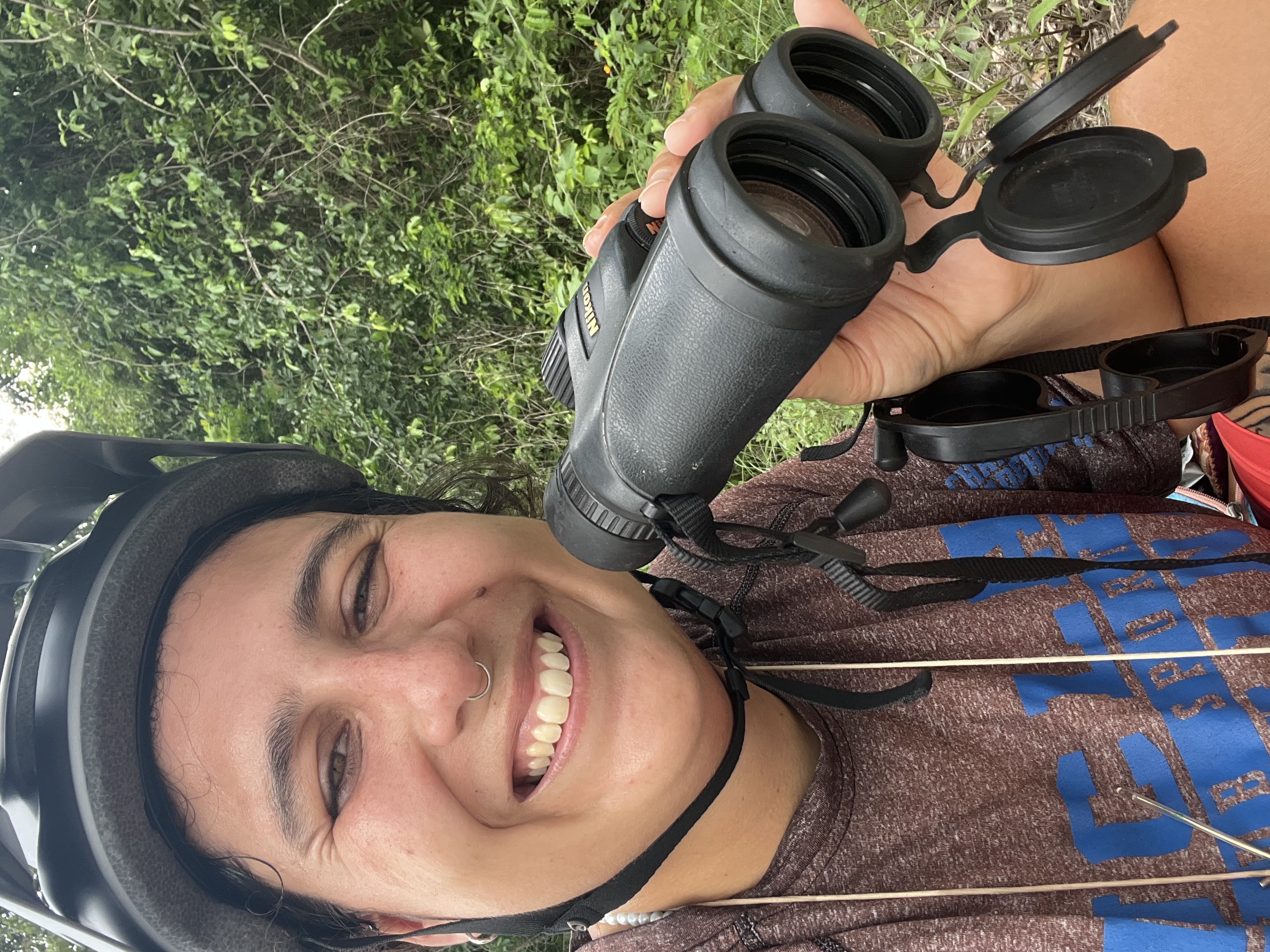Santi holding binoculars while birding in the jungle near Tulum