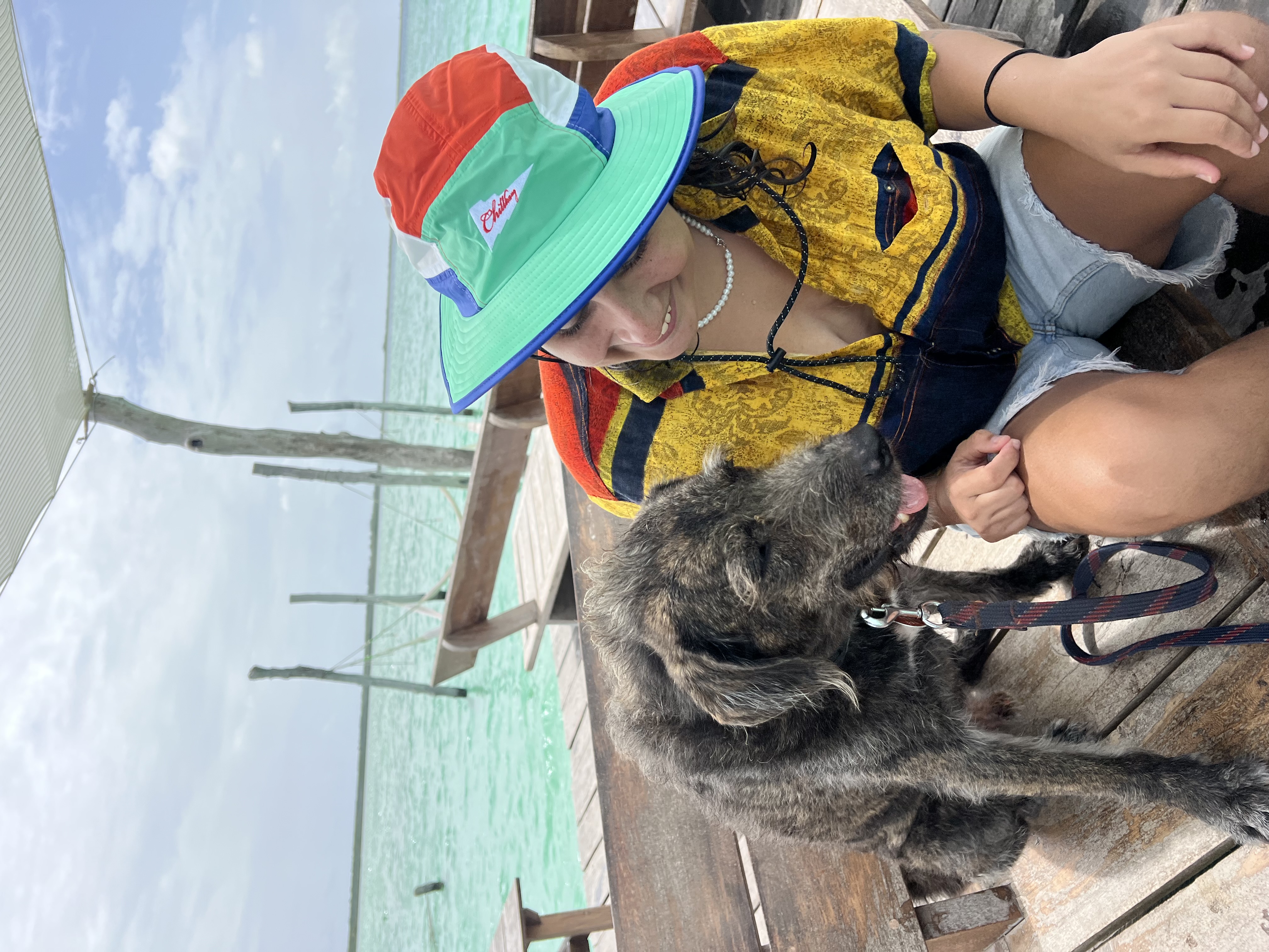 Santi sitting with a dog on a dock over the lagoon in Tulum