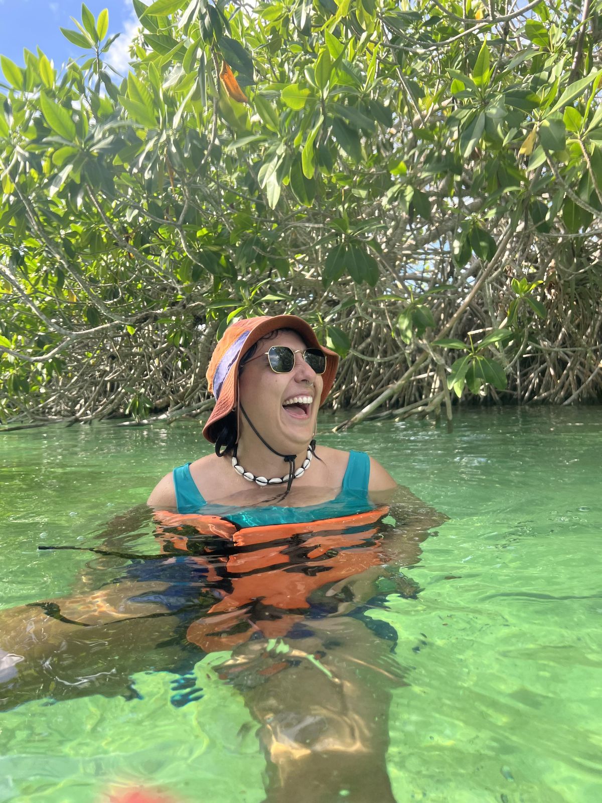 Santi laughing in the water near Tulum, wearing a life vest
