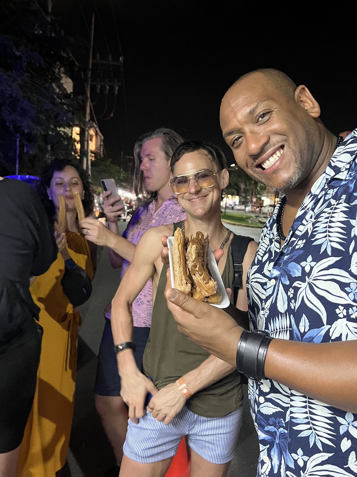Friends holding churros on a Tulum street food tour at night