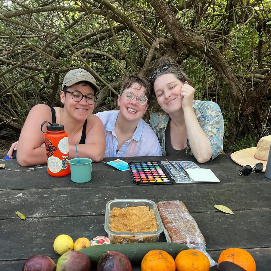 Friends painting together over a spread of fresh fruit in the jungle near Tulum